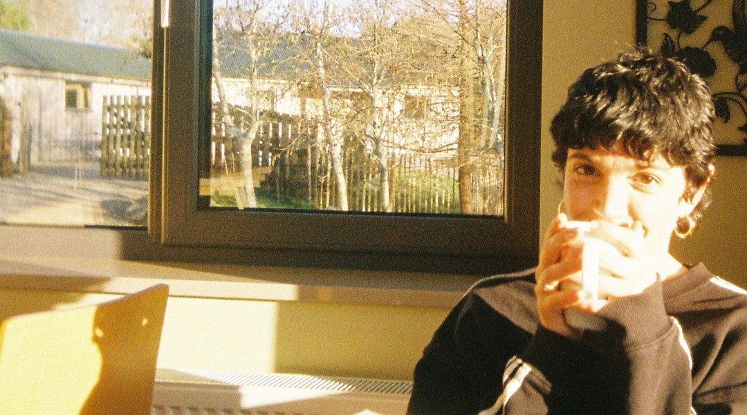 Blanca holding a cup by a window